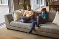 Two caucasian boys using laptop and digital tablet sitting on the couch at home Royalty Free Stock Photo