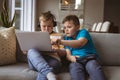 Two caucasian boys using laptop sitting on the couch at home Royalty Free Stock Photo