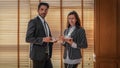 Two caucasian businesspeople standing and holding coffee or tea cup in office