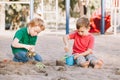 Two Caucasian children sitting in sandbox playing with beach toys. Little boys friends having fun together on playground. Summer Royalty Free Stock Photo