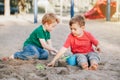 Two Caucasian children sitting in sandbox playing with beach toys. Little boys friends having fun together on playground. Summer Royalty Free Stock Photo