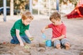 Two Caucasian children sitting in sandbox playing with beach toys. Little boys friends having fun together on a playground. Summer Royalty Free Stock Photo