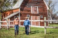 Two caucasian cowboys talking to each other as they are walking away from the barn. Royalty Free Stock Photo