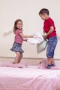 Two Caucasian Kids Having a Funny Pillow Battle on Bed Indoors Royalty Free Stock Photo