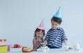 Two Caucasian kids little boy and girl enjoy eating birthday cake with hands at home on white background Royalty Free Stock Photo