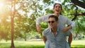 Two caucasian lover couple having romance moment in park together. Boyfriend carrying his girlfriend on piggyback