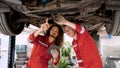 Two Caucasian male mechanics wearing red mechanic Checking for car damage received from accident To prepare