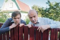 Two caucasian men carefully watching over the fence.