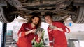 Two Caucasian men are helping to repair car that was lifted up to be repaired under car in garage. mechanic is helping Royalty Free Stock Photo