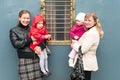 Two Caucasian mothers holding their daughters on arms, smiling and looking at camera