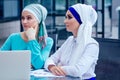 Two caucasian Muslim office lady discussing with a businesswoman partner job interview in office shawl and turban on her Royalty Free Stock Photo