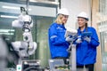 Two Caucasian professional engineer or technician woman workers hold controller and tablet help to check and maintenance robotic Royalty Free Stock Photo