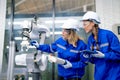 Two Caucasian professional engineer or technician woman workers hold controller and tablet help to check and maintenance robotic Royalty Free Stock Photo