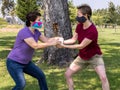 Two Caucasian women fighting over a roll of toilet paper at a park