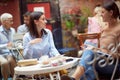 Two caucasian young adult women sitting in the outdoor cafe, talking, socializing, smiling, looking each other Royalty Free Stock Photo