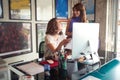 Two caucasian young female colleagues talking at work, looking each other, smiling. enjoying at work, loving their job Royalty Free Stock Photo