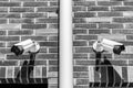 Two cctv surveillance security system cameras on the brick wall of luxury residential building for public and private safety black