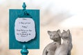 Two ceramic cats sit next to a memory board with a handwritten reminder about happy cats