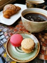 Two ceramic cups of black coffee with croissants and macaroni cakes on a vintage table Royalty Free Stock Photo