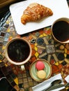 Two ceramic cups of black coffee with croissants and macaroni cakes on a vintage table Royalty Free Stock Photo