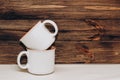 Two ceramic light mugs on a background of wooden boards.