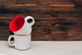 Two ceramic light mugs, inside red on a background of wooden boards.