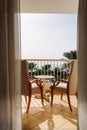 Two chairs and table on a balcony overlooking the Sea with grass and palm trees. Royalty Free Stock Photo