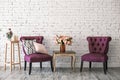 Two chairs and a table with bouquet of flowers in a vase near white brick wall vintage style