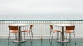 Two chairs and a table on a deck overlooking the ocean, AI