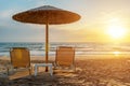 Two chairs under beach umbrella on tropical beach during sunset. Summer vacation concept Royalty Free Stock Photo