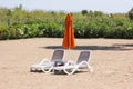 Two chaise lounges stand on the sand with a closed umbrella Royalty Free Stock Photo