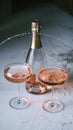 Two champagne flutes with pink champagne and opened bottle Royalty Free Stock Photo