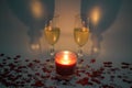 Two champagne glasses with a candle surrounded by heart shaped confetti