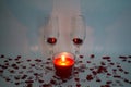 Two champagne glasses with a candle surrounded by heart shaped confetti