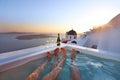 Two champagne glasses on the edge of infinity swimming pool at sunset on Santorini island