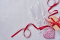 Two champagne glasses, a gift box, a beautiful serge and a red ribbon on a sparkling gray background. Valentine day greeting card