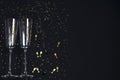 Two champagne glasses, golden confetti on a festive black background. Festive Christmas, New Year concept. Copy space Royalty Free Stock Photo