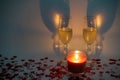 Two champagne glasses with a candle surrounded by heart shaped confetti