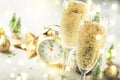 Two champagne glasses with moving bubbles and christmas decoration over gray golden bokeh background. Happy New Year Celebration.