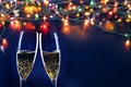 two champagne glasses ready to bring in the New Year - holiday lights and fireworks in the background