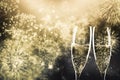 two champagne glasses ready to bring in the New Year - holiday lights and fireworks in the background Royalty Free Stock Photo