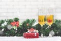 Two champagne glasses setting next to a red gift box on snowy ta