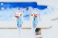 Two champagne glasses with strawberry on sunny terrace outdoor patio overlooking swimming pool at summer day outside of Royalty Free Stock Photo