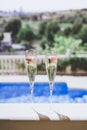 Two champagne glasses with strawberry on sunny terrace outdoor patio overlooking swimming pool at summer day outside of Royalty Free Stock Photo