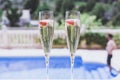 Two champagne glasses with strawberry on sunny terrace outdoor patio overlooking swimming pool at summer day outside of Royalty Free Stock Photo