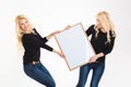 Two charming blonde sisters twins having fun holding blank board Royalty Free Stock Photo