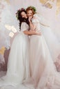 Two charming brides in beautiful spring wreaths on their heads. Beautiful young women in wedding dresses