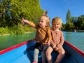 Two charming little kids in the small paddle pond boat