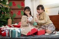 Two cheerful little Asian girls are enjoying opening their Christmas gifts in the living room Royalty Free Stock Photo