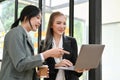 Two cheerful Asian businesswomen discussing and working together, looking at laptop screen Royalty Free Stock Photo